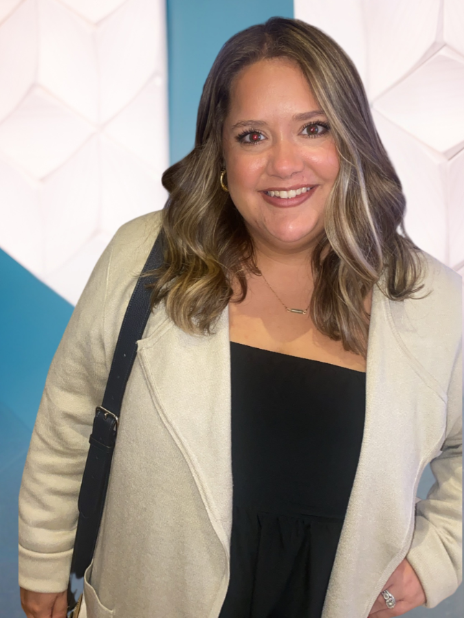 Woman smiling in front of a colorful wall.